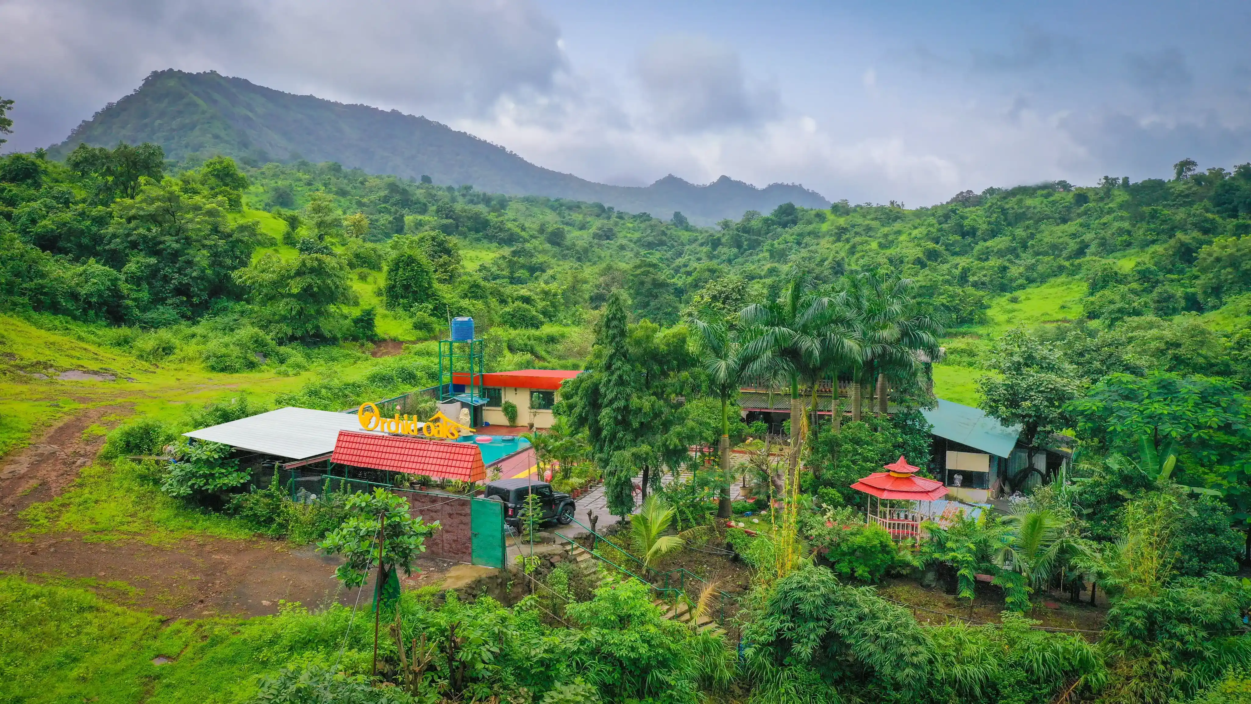 Aerial view of Orchid Oaks Homestead Resort surrounded by natural landscape near Gadeshwar Dam