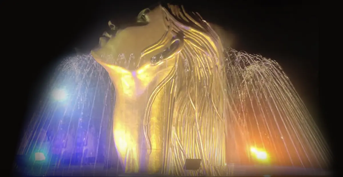 Stunning golden face fountain illuminated with colorful water jets at night, a captivating public art display.